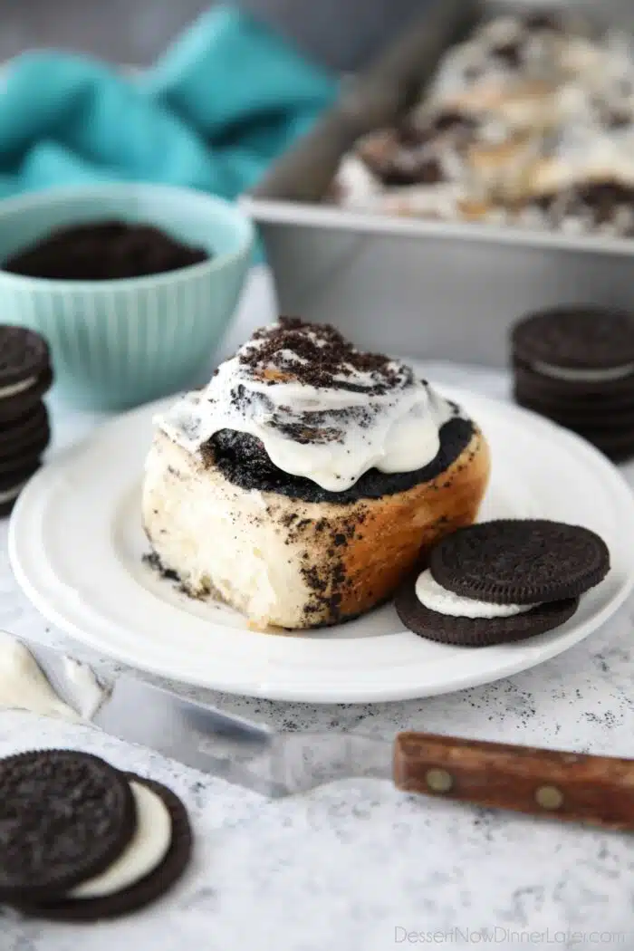 Side view of an Oreo filled cinnamon roll with cream cheese frosting.