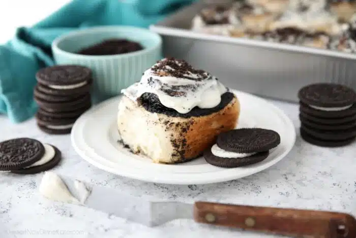 Side view of an Oreo filled cinnamon roll with cream cheese frosting.