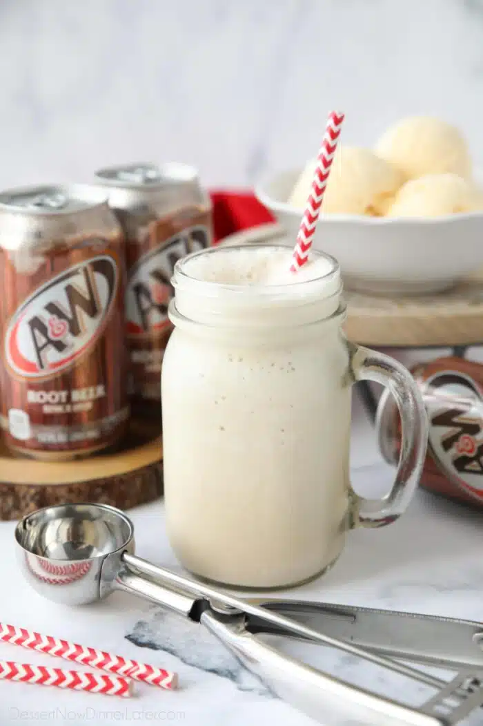 Mason jar mug full of root beer shake and a straw.