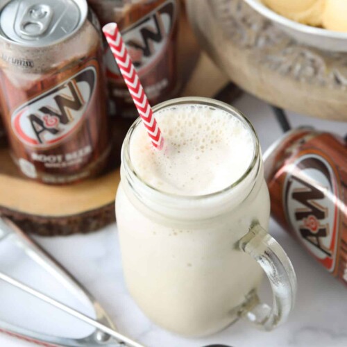 Mason jar mug full of root beer milkshake and a straw.