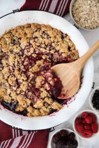 Spooning berry crisp (aka berry crumble) out of dish.