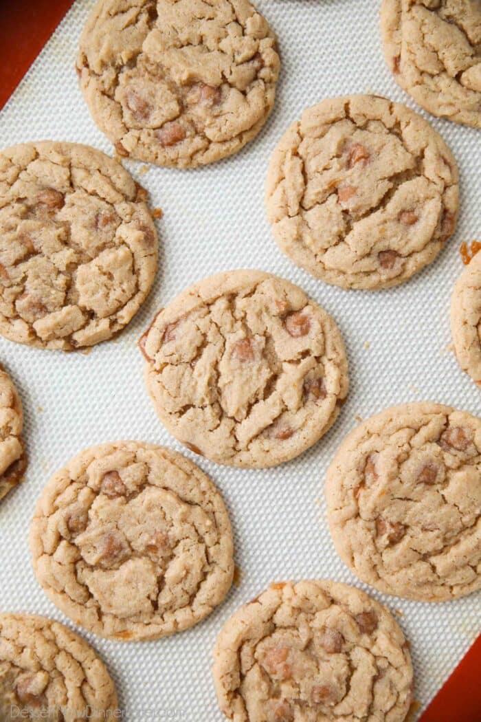 Apple cider cookies with caramel bits on a silicone lined sheet tray.