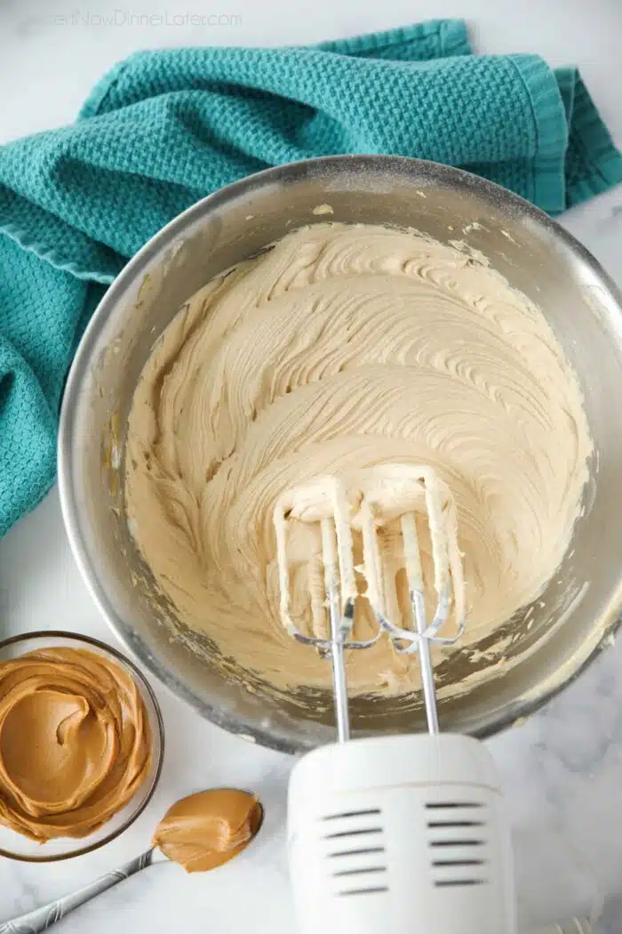 Bowl of peanut butter frosting made with an electric and mixer.