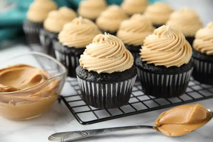 Peanut butter frosting piped on top of chocolate cupcakes.