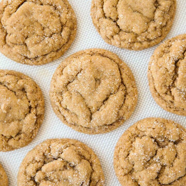 Baked pumpkin gingersnap cookies on a silicone baking mat.