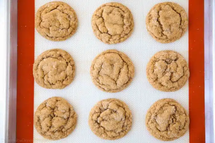 Baked pumpkin gingersnap cookies on a silicone baking mat.