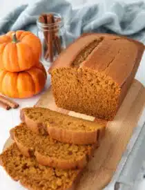 Loaf of pumpkin bread on a cutting board with some slices cut.