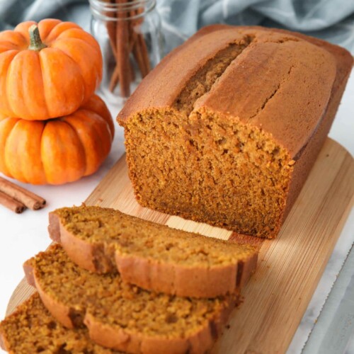 Loaf of pumpkin bread on a cutting board with some slices cut.