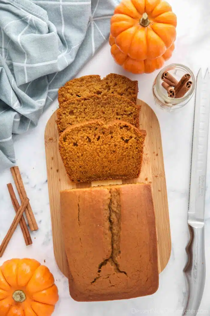 Pumpkin loaf cake on a cutting board with a few slices cut off.