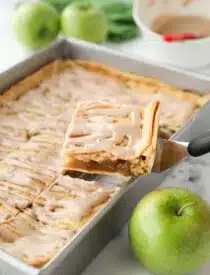 Scooping a piece of Apple Slab Pie out of a 9x13 inch pan.