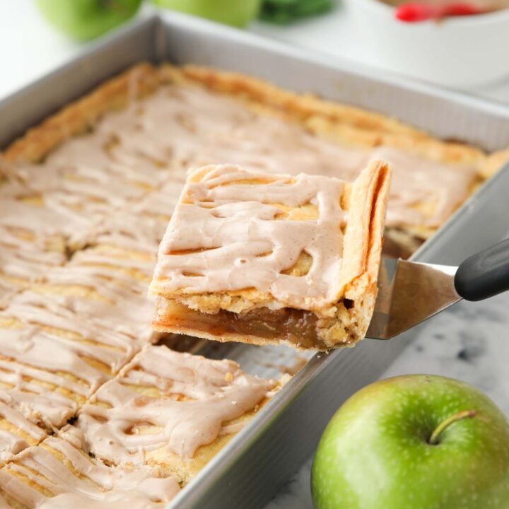Scooping a piece of Apple Slab Pie out of a 9x13 inch pan.