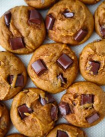 Closeup of pumpkin chocolate chunk cookies on a silicone baking mat.