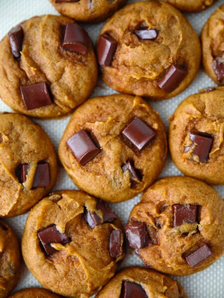 Closeup of pumpkin chocolate chunk cookies on a silicone baking mat.