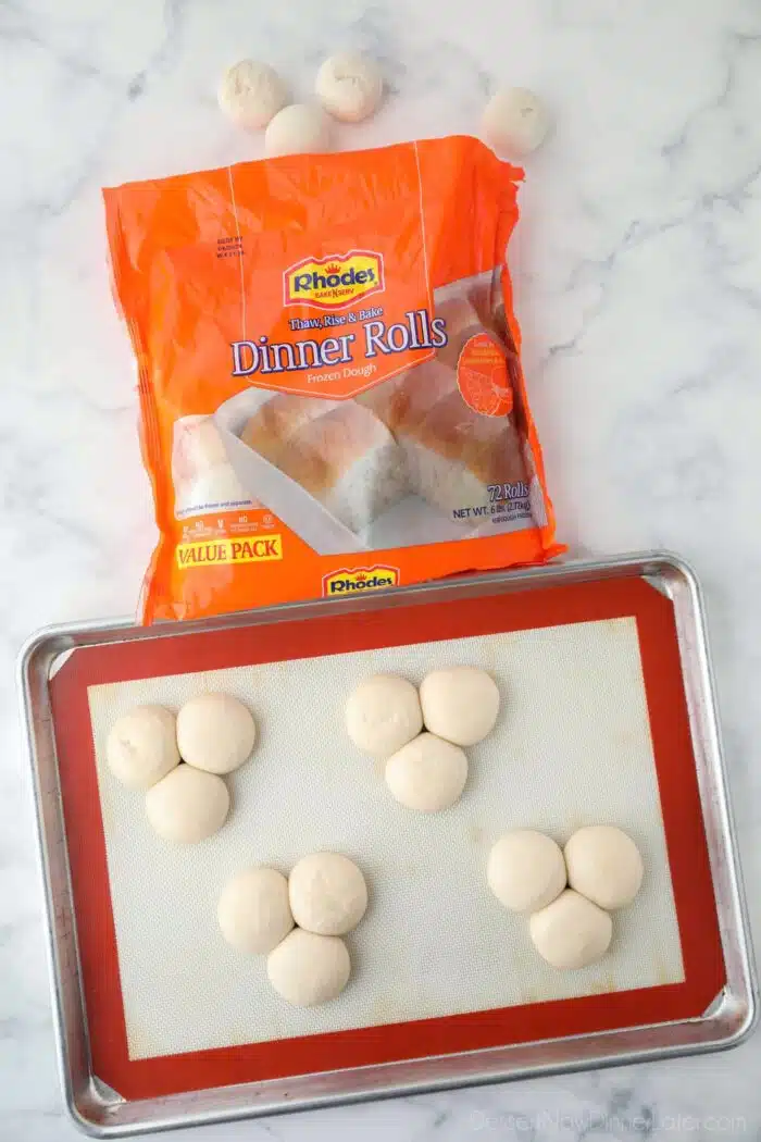 Package of Rhodes rolls with four groups of three rolls close-together; thawed on a sheet pan.