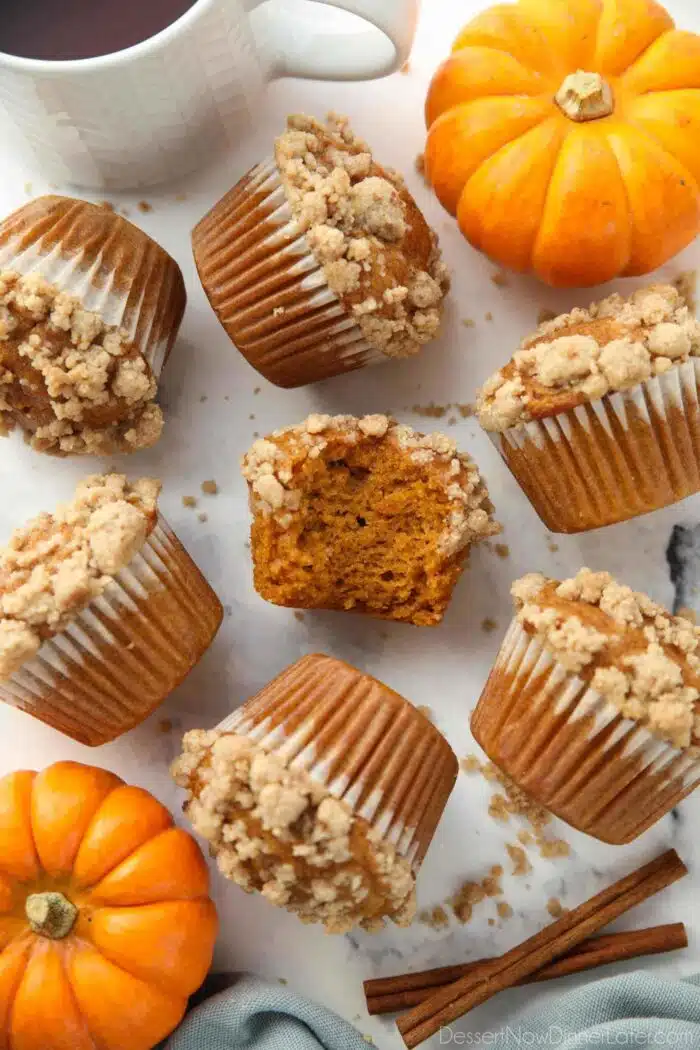 Pumpkin streusel muffins laying on their sides. One in the center with a bite taken out.