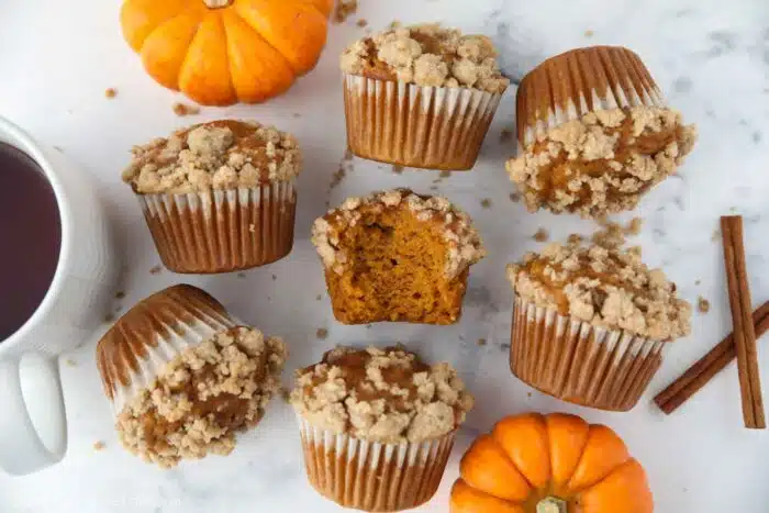 Pumpkin streusel muffins laying on their sides. One in the center with a bite taken out.