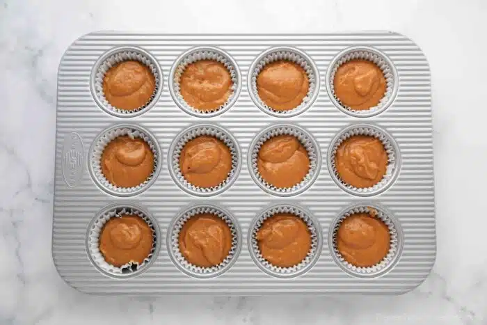 Pumpkin cake batter in a paper lined cupcake pan.