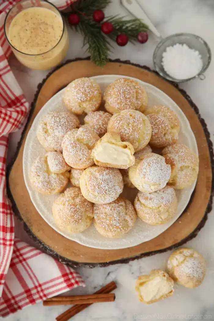 Top view of eggnog cream puffs with one cut open in the center.