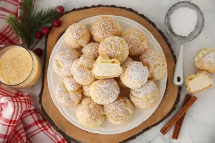 Top view of egg nog cream puffs with one cut open in the center.