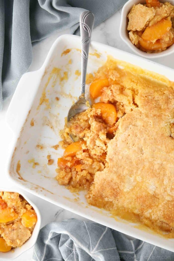 Top view of peach dump cake in pan being scooped with a spoon.
