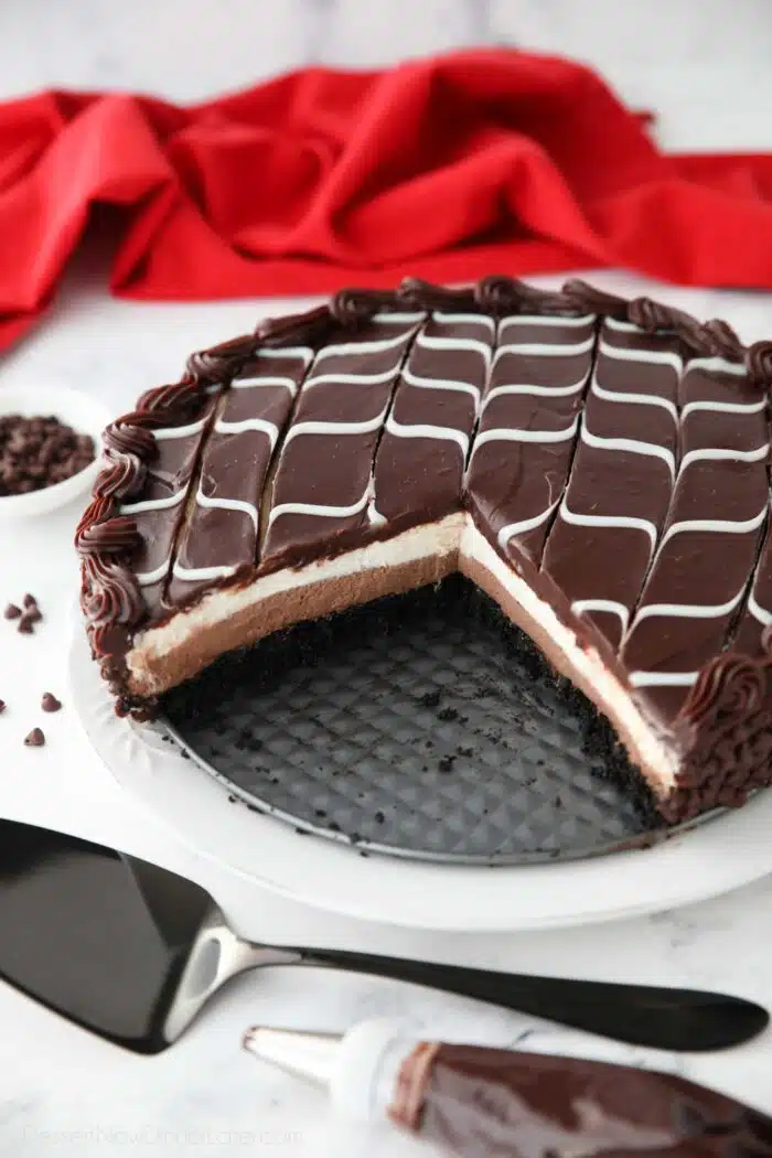 Copycat Olive Garden Black Tie Mousse Cake missing a couple of pieces to show layers of chocolate cake, chocolate mousse, vanilla mousse, with swirled white and dark chocolate ganache on top.