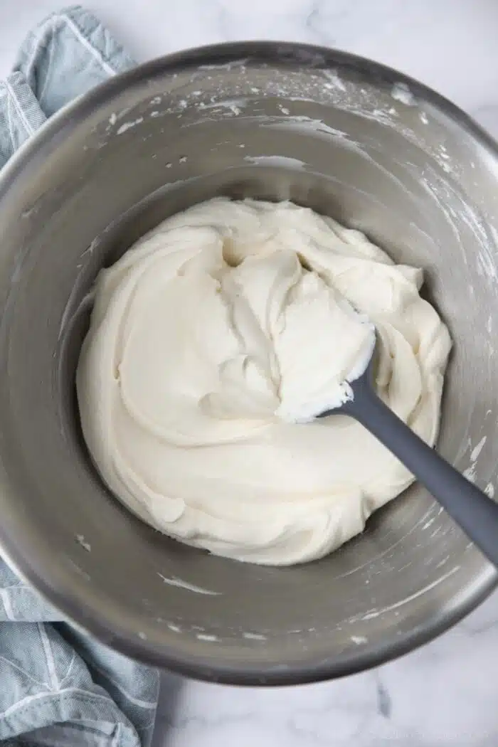 The best cream cheese frosting in a bowl with a spatula.