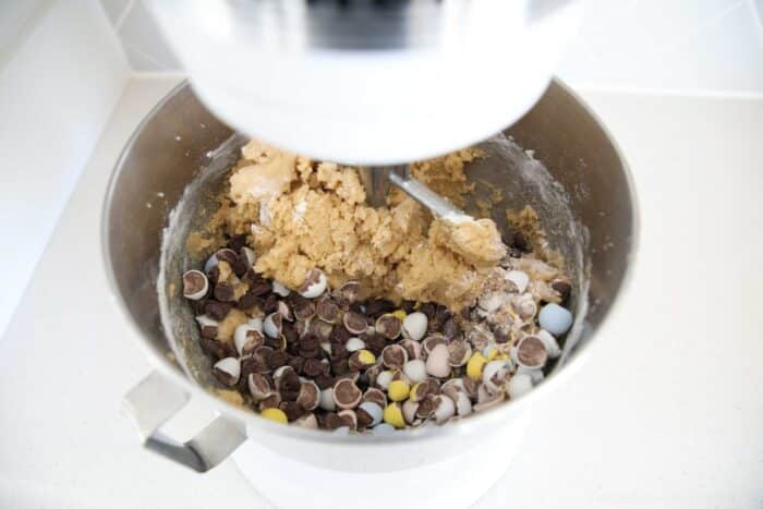 Adding chocolate chips and crushed mini Cadbury eggs to cookie dough.