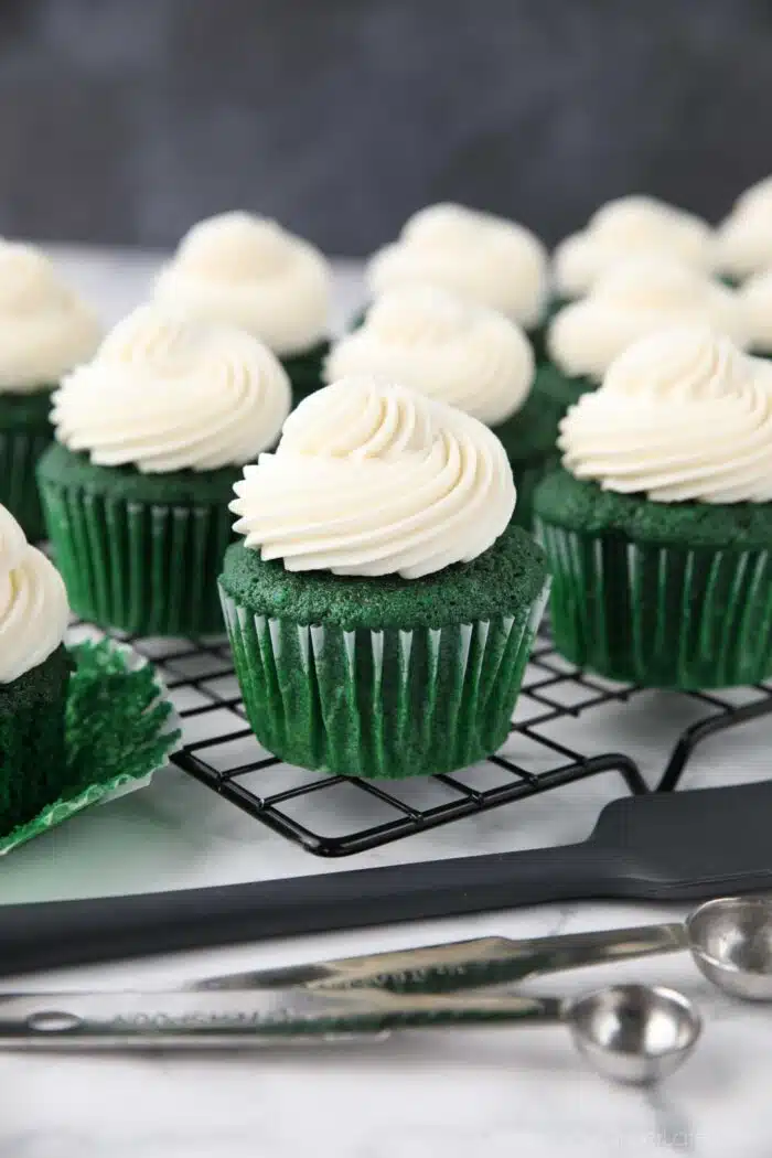 Close up of green velvet cupcakes with whipped cream cheese frosting piped on top.