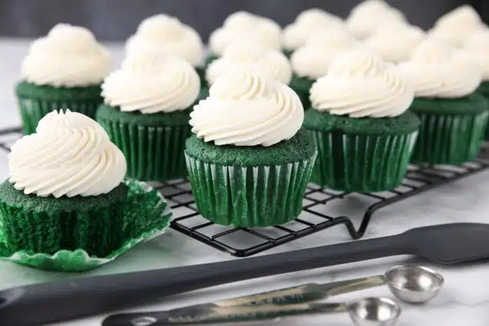 Close up of green velvet cupcakes with whipped cream cheese frosting piped on top.