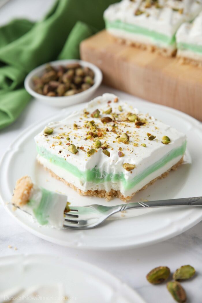 Layered pistachio dessert on a plate with a fork-full taken out.