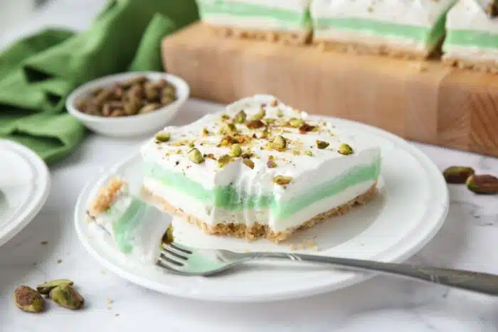 Layered pistachio dessert on a plate with a fork-full taken out.