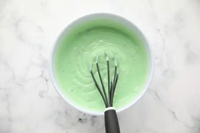 Instant pistachio pudding being whisked in a bowl.