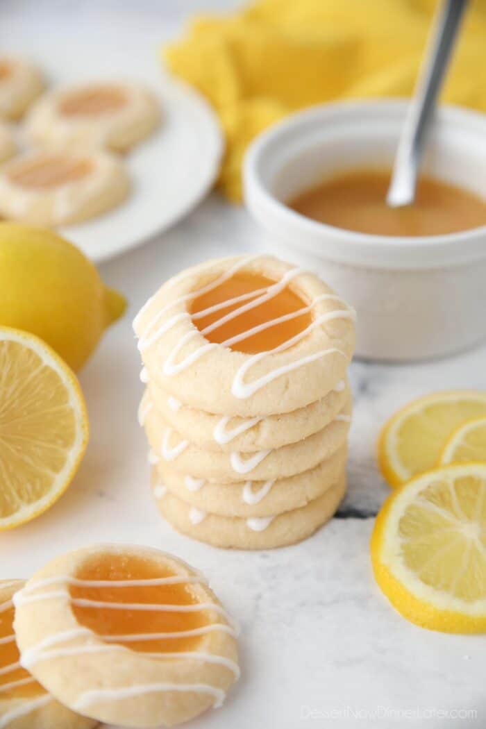 Stack of lemon thumbprint cookies with glaze drizzled on top.