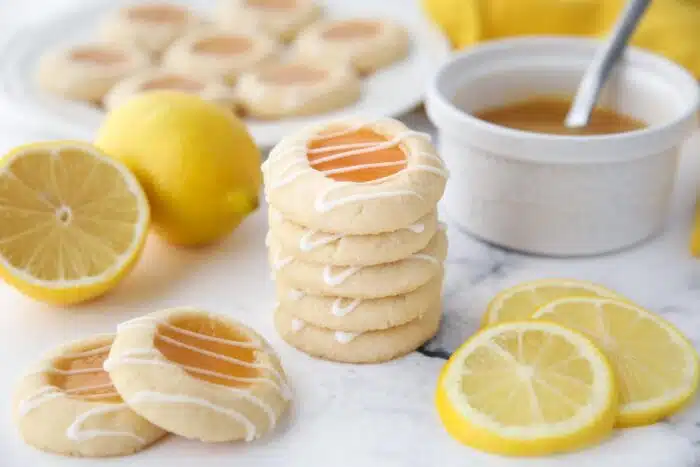 Stack of lemon thumbprint cookies with glaze drizzled on top.