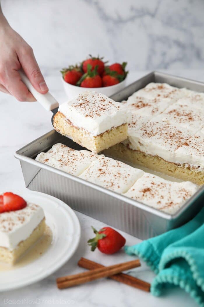 Scooping a piece of tres leches cake out of the pan.