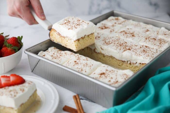 Scooping a piece of tres leches cake out of the pan.