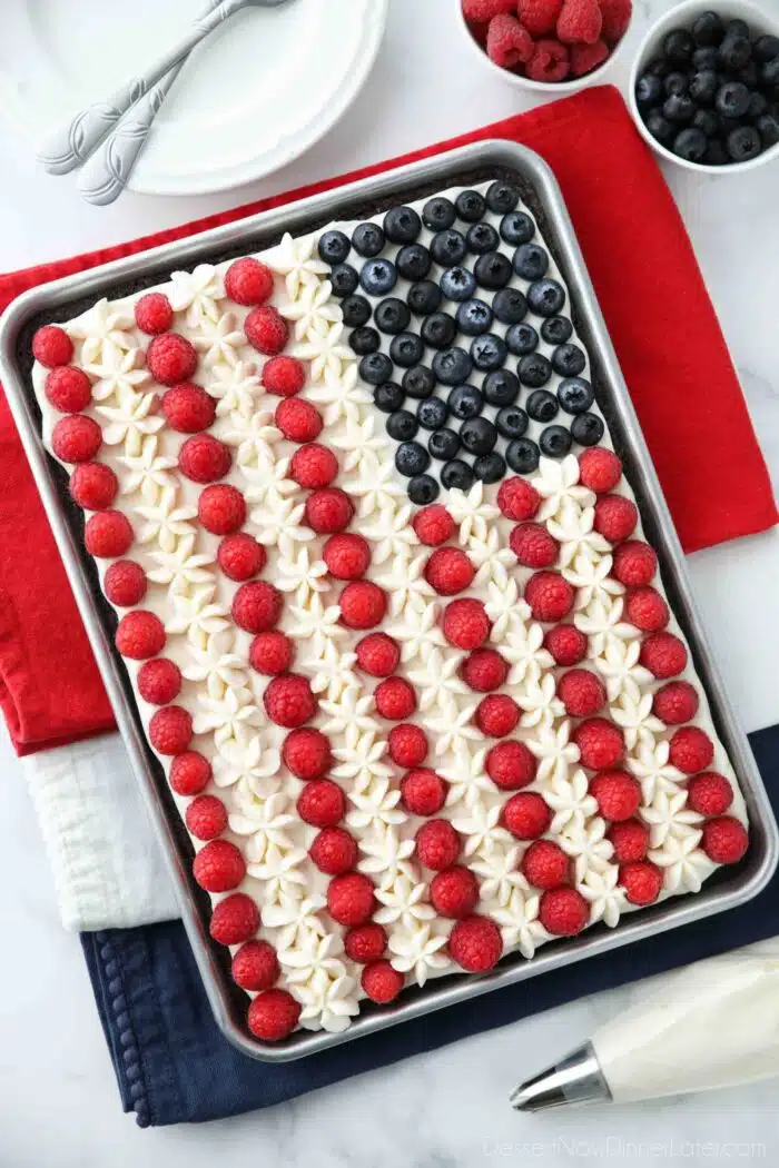 American flag brownie fruit pizza decorated with whipped cream cheese frosting, blueberries and raspberries for the stars and stripes.