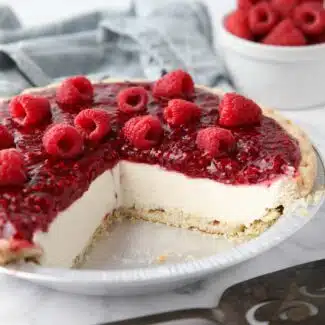 Slices removed from pie pan to show the inside of Raspberry Cream Pie with a pastry crust, whipped cream cheese filling and raspberry topping.