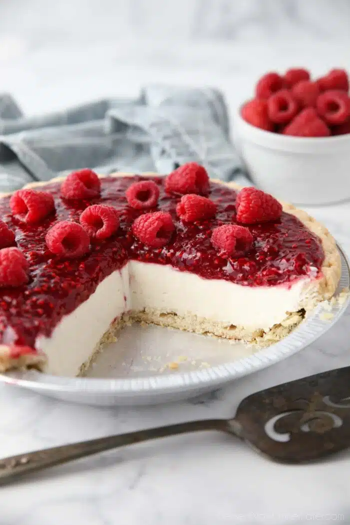 Slices removed from pie pan to show the inside of Raspberry Cream Pie with a pastry crust, whipped cream cheese filling and raspberry topping.