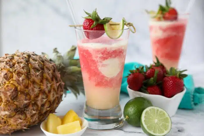 Two glasses of Miami Vice mocktail -- a mixture of non-alcoholic pina colada and strawberry daiquiri drinks swirled together.