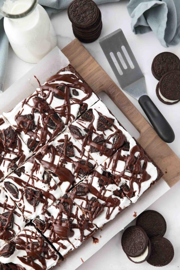 Cookies and Cream Brownies with marshmallow frosting, Oreo cookies, and fudge sauce drizzled on top.