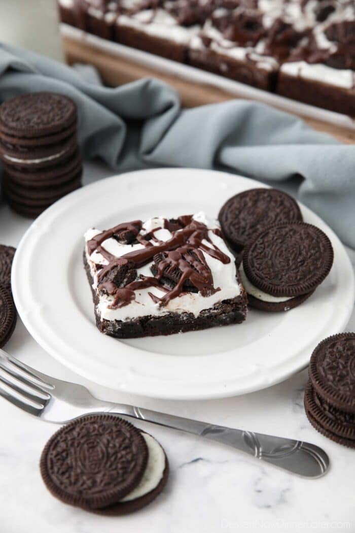 A Cookies and Cream Brownie on a plate with Oreo cookies on the side.