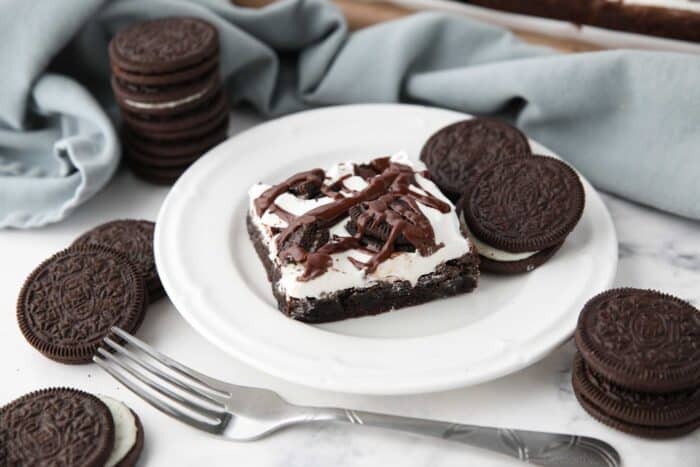 A Cookies and Cream Brownie on a plate with Oreo cookies on the side.