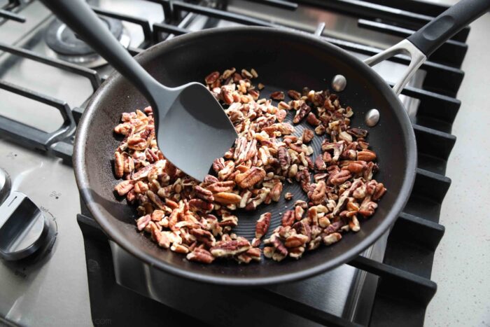 Toasting chopped pecans in a skillet.