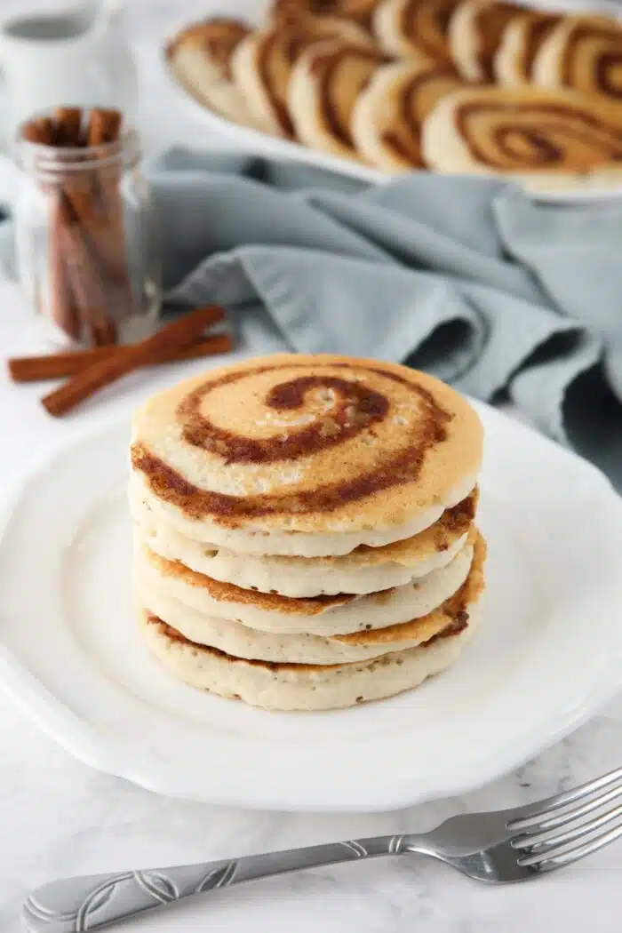 Stack of cinnamon roll pancakes on a plate.
