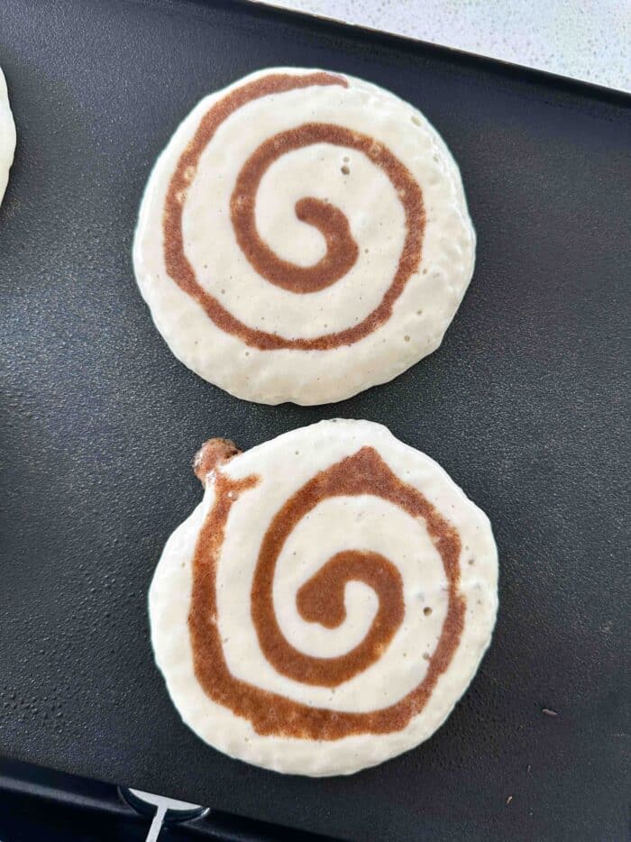 Cooking cinnamon swirl pancakes on a griddle.
