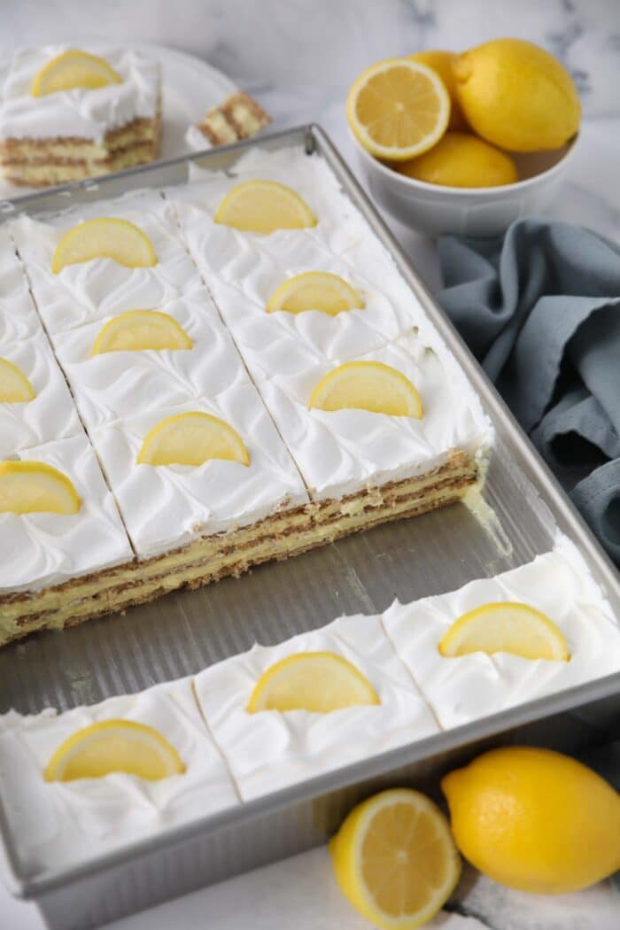 Lemon icebox cake in pan with layers of graham crackers, lemon pudding, and Cool Whip.