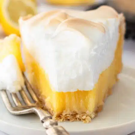 Slice of lemon meringue pie on a plate with a forkful taken out.