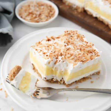 Slice of coconut delight on a plate with a forkful taken out.