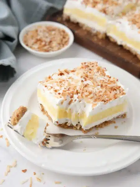 Slice of coconut delight on a plate with a forkful taken out.